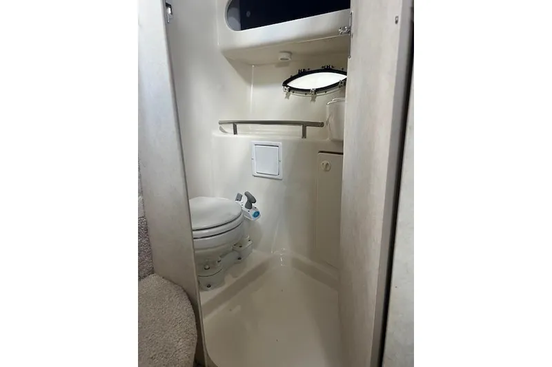 Slide: The Image of 1999 Bayliner 3055 Ciera Sunbridge bathroom with toilet, sink, and porthole window. - 31