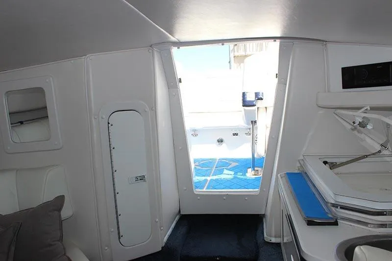 Slide: The Image of Interior view of a 2000 Fountain 32 Fever boat, featuring white cabin and blue flooring. - 46