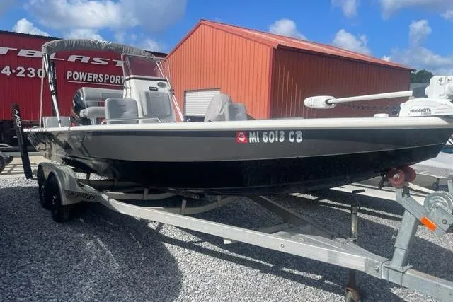 Slide: The Image of 2021 Avid 23 Fusion boat on trailer, parked near red building under blue sky. - 2
