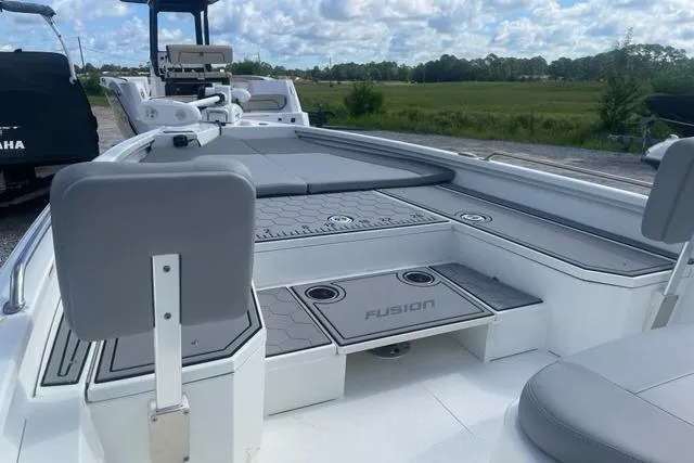 Slide: The Image of Avid 23 Fusion 2021 boat interior with seating and deck, under a cloudy sky. - 6