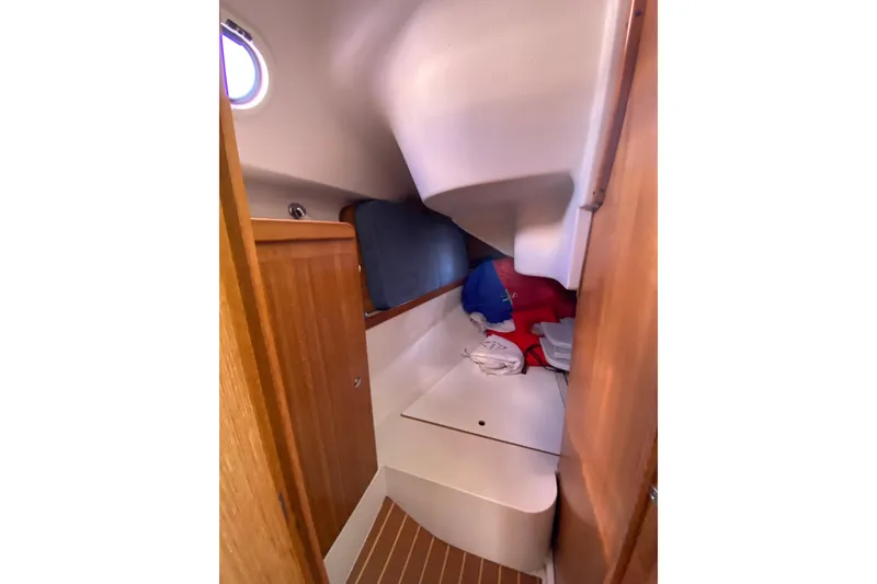 Slide: The Image of 2006 Catalina 309 sailboat interior cabin with wooden cabinetry and storage space. - 14