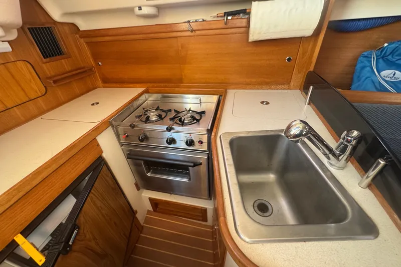 Slide: The Image of Compact kitchen in 2006 Catalina 309 sailboat with stove, sink, and wooden cabinetry. - 47