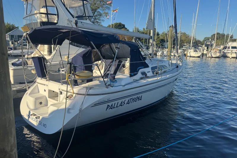 Slide: The Image of 2006 Catalina 309 sailboat docked in marina, named "Pallas Athena," with blue canopy. - 62