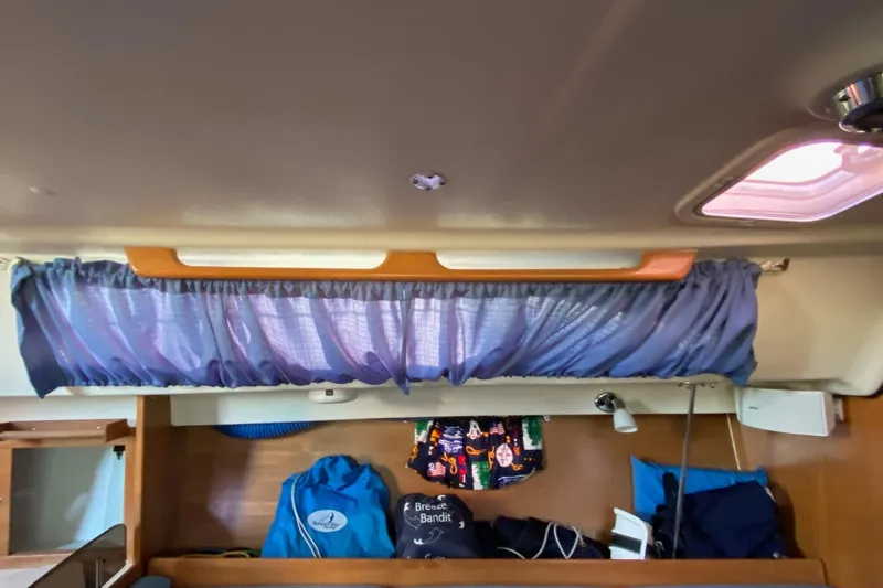 Slide: The Image of Interior of a 2006 Catalina 309 sailboat with blue curtains and storage area. - 64