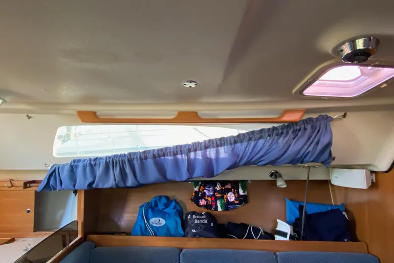 Slide: The Image of Interior of a 2006 Catalina 309 sailboat with blue curtains and storage area. - 65