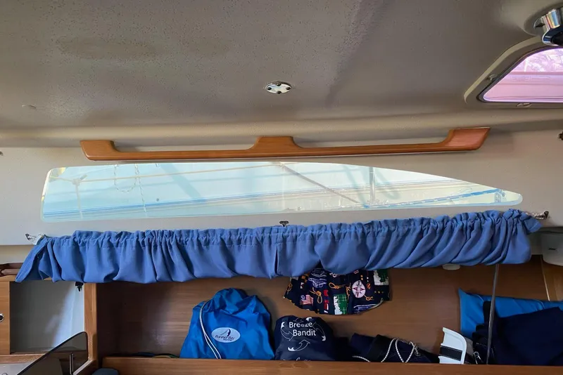 Slide: The Image of Interior view of a 2006 Catalina 309 sailboat with blue curtains and storage. - 66