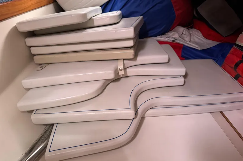 Slide: The Image of Stacked white cushions inside a 2006 Catalina 309 sailboat cabin. - 73