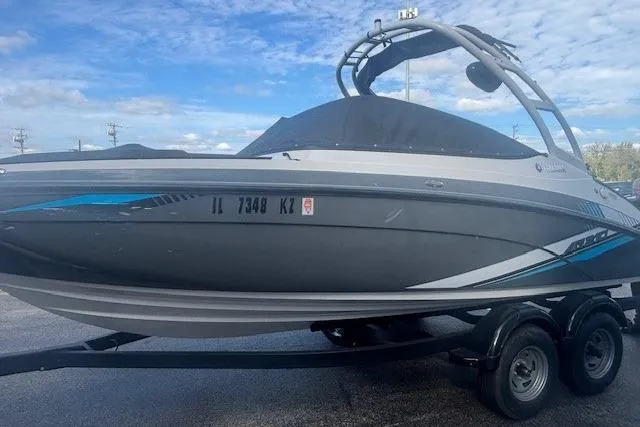 Slide: The Image of 2020 Yamaha AR210 boat on trailer, sleek design with blue accents, under a clear sky. - 2