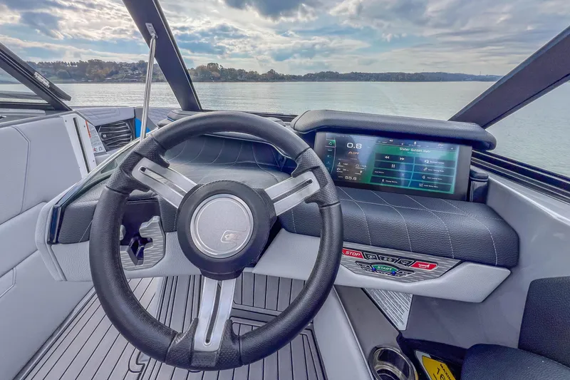 Slide: The Image of 2022 Nautique Super Air Nautique G23 dashboard with steering wheel and digital display on a lake. - 16