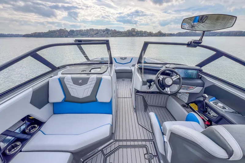Slide: The Image of 2022 Nautique Super Air Nautique G23 interior with modern dashboard and seating on a calm lake. - 17
