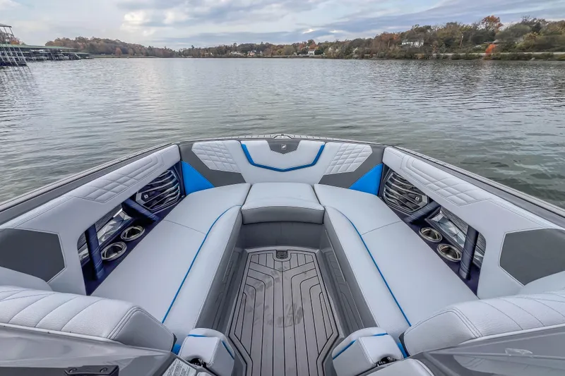 Slide: The Image of 2022 Nautique Super Air Nautique G23 boat interior with luxurious seating on a calm lake. - 24