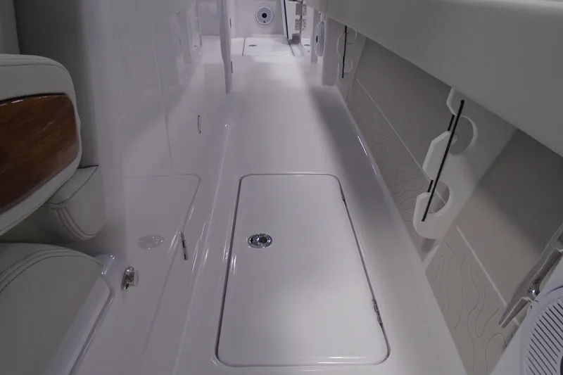 Slide: The Image of Interior view of a 2026 Jupiter 32 boat, featuring sleek white flooring and storage compartments. - 21
