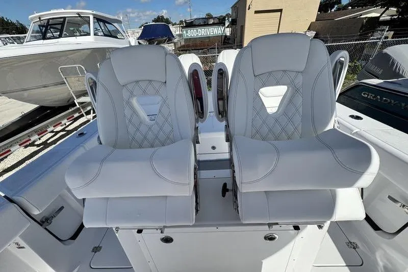Slide: The Image of 2026 Sportsman Heritage 261 Center Console boat seats, white upholstery, diamond stitching, outdoor setting. - 24