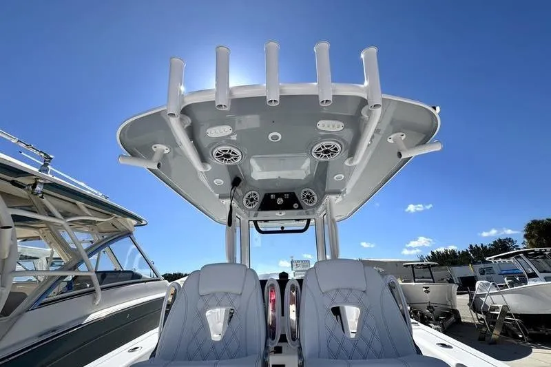 Slide: The Image of 2026 Sportsman Heritage 261 Center Console boat with T-top and rod holders under clear sky. - 37