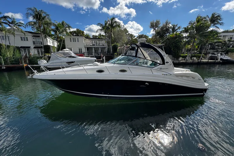The Image of 2006 Sea Ray 340 Sundancer yacht docked in a scenic waterfront setting with palm trees. - 0