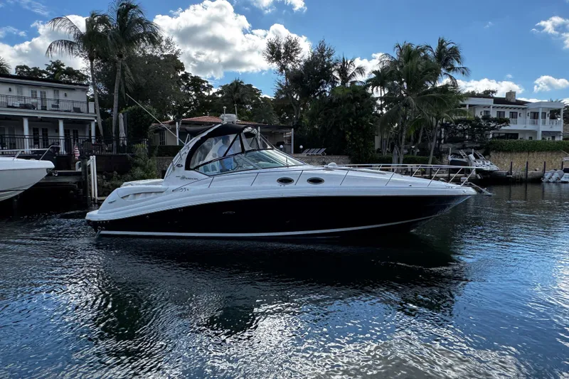 Slide: The Image of 2006 Sea Ray 340 Sundancer yacht docked near waterfront homes, under a partly cloudy sky. - 4