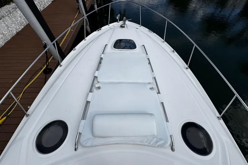 Slide: The Image of 2006 Sea Ray 340 Sundancer boat deck with sun pad and railing, docked by water. - 50