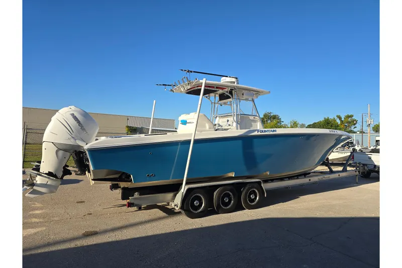 Slide: The Image of 2012 Fountain 38 Center Console boat on trailer, blue hull, triple outboard engines. - 15