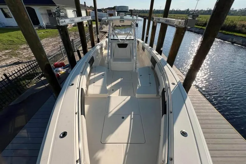 Slide: The Image of 2012 Fountain 38 Center Console boat interior with helm and seating, docked by the water. - 7