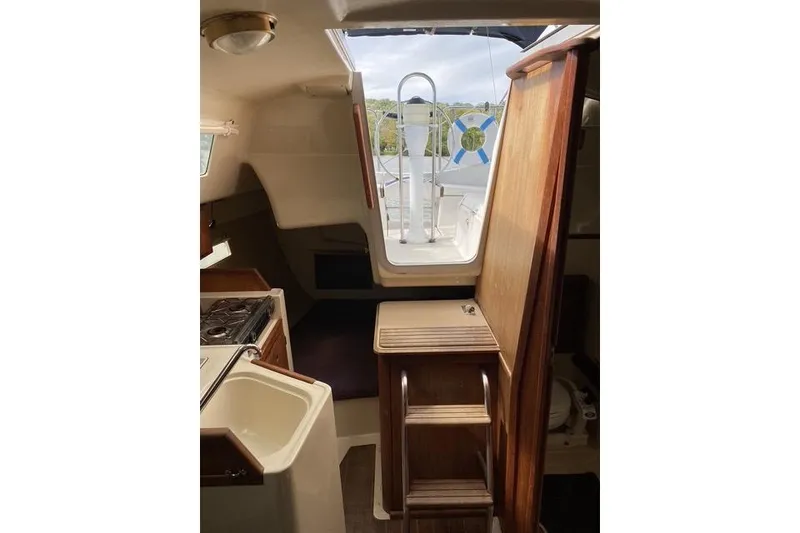 Slide: The Image of Interior of a 1990 Hunter 27 sailboat, featuring a compact kitchen and wooden cabinetry. - 11
