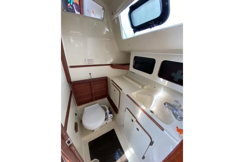 Slide: The Image of 1990 Hunter 27 yacht bathroom with toilet, sink, and storage cabinets. - 14