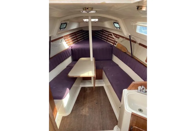 Slide: The Image of Interior of a 1990 Hunter 27 sailboat with purple seating and a compact dining area. - 17