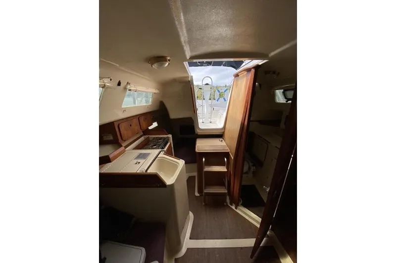 Slide: The Image of Interior of a 1990 Hunter 27 sailboat, featuring a compact kitchen and wooden cabinetry. - 20