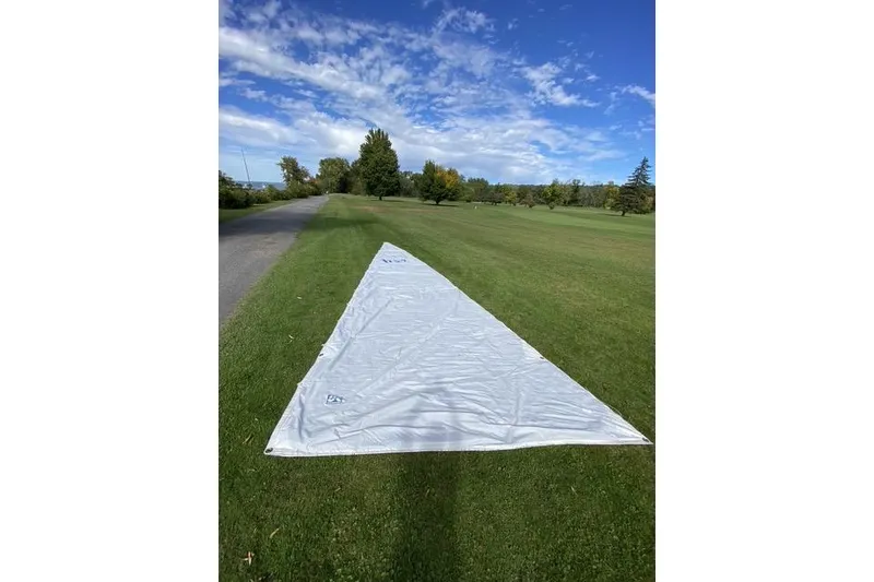Slide: The Image of White sail from a 1990 Hunter 27 yacht laid out on grass under a blue sky. - 23