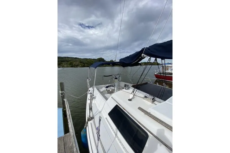 Slide: The Image of 1990 Hunter 27 sailboat docked on a cloudy day, featuring a blue canopy. - 3