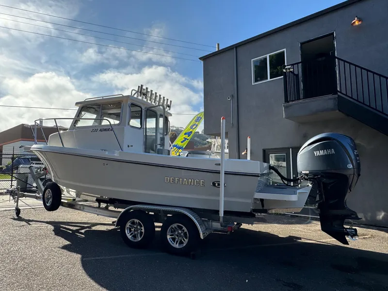 Slide: The Image of 2025 Defiance Admiral 220 EX boat on trailer, parked outdoors, with Yamaha outboard motor. - 2