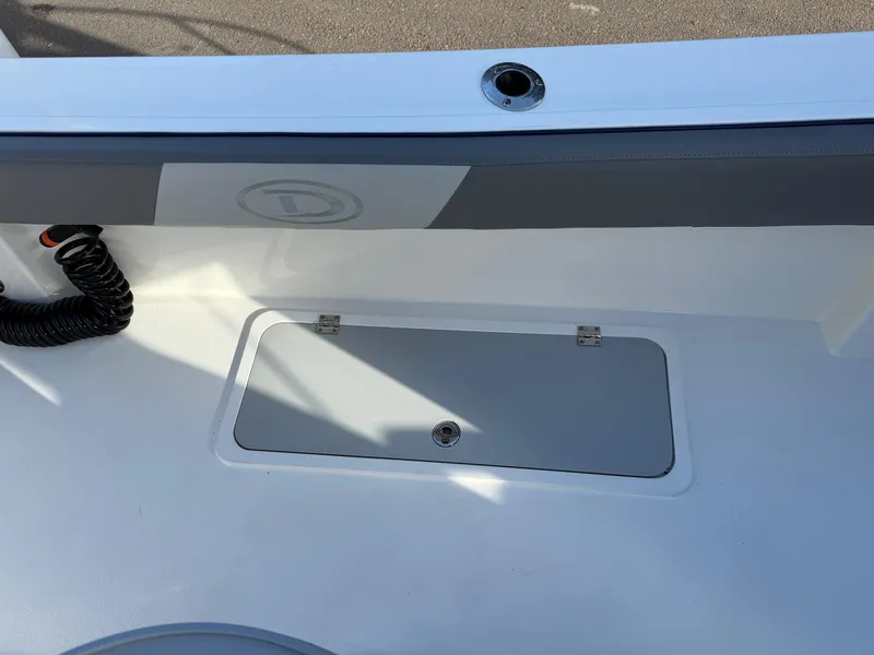 Slide: The Image of 2025 Defiance Admiral 220 EX boat deck with storage compartment and coiled cable. - 24