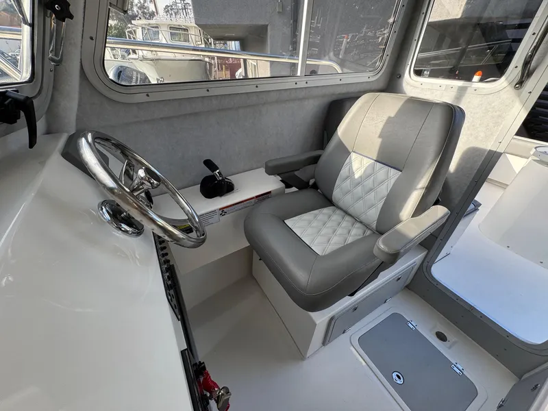 Slide: The Image of 2025 Defiance Admiral 220 EX boat interior with steering wheel and cushioned seat. - 44