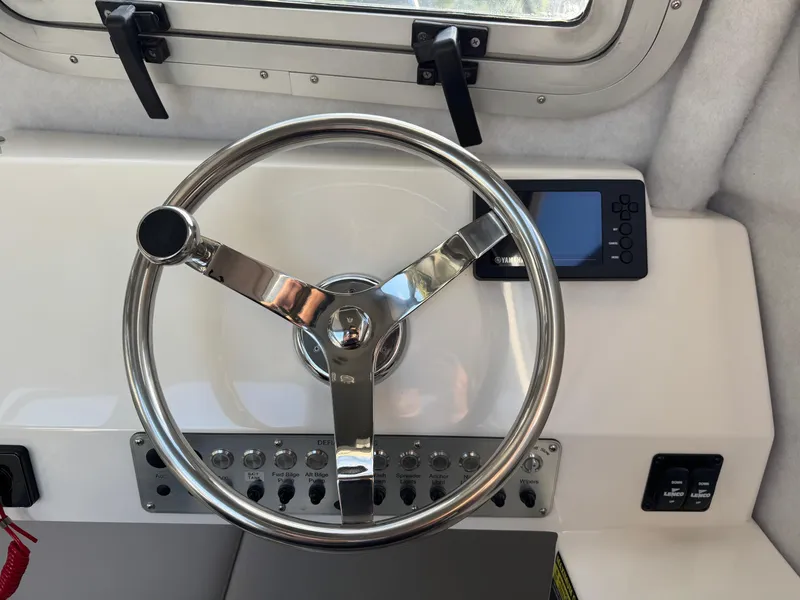 Slide: The Image of Steering wheel of 2025 Defiance Admiral 220 EX boat with control panel and window view. - 48