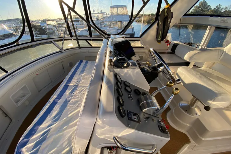Slide: The Image of 1998 Carver 445 Aft Cabin Motor Yacht helm with striped seating and navigational controls. - 13