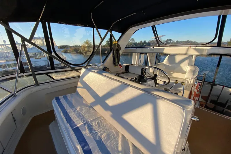 Slide: The Image of 1998 Carver 445 Aft Cabin Motor Yacht interior with helm, seating, and scenic water view. - 14