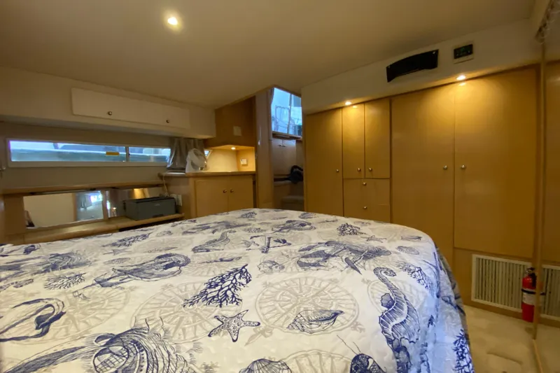 Slide: The Image of 1998 Carver 445 Aft Cabin Motor Yacht bedroom with nautical-themed bedding and wooden cabinetry. - 31