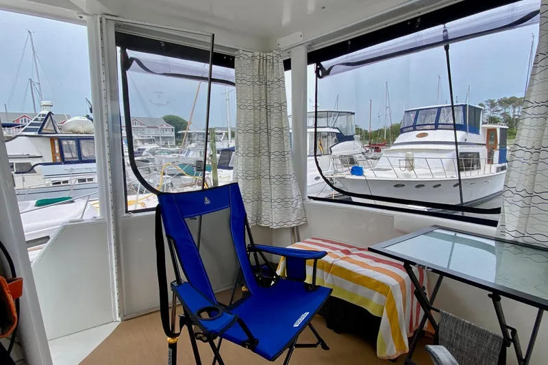 Slide: The Image of 1998 Carver 445 Aft Cabin Motor Yacht interior with marina view, featuring blue chair and table. - 10