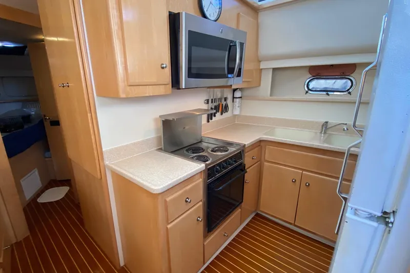 Slide: The Image of 1998 Carver 445 Aft Cabin Motor Yacht kitchen with stove, microwave, and wooden cabinetry. - 26