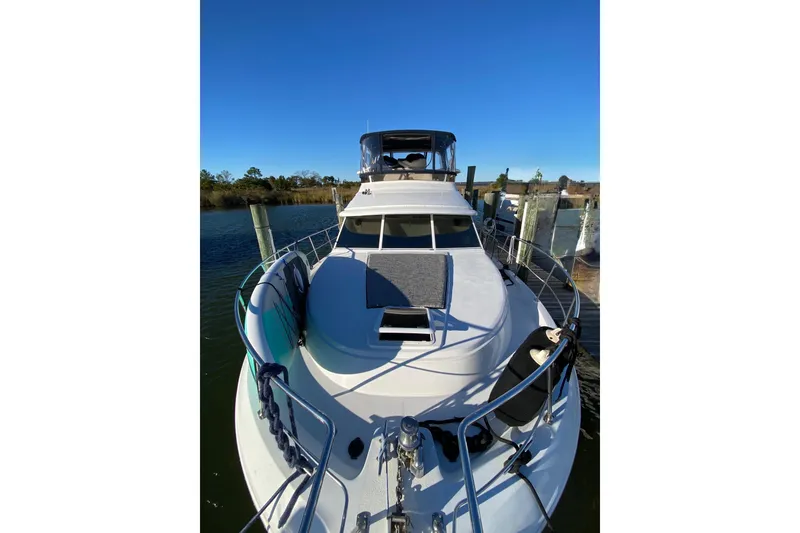 Slide: The Image of 1998 Carver 445 Aft Cabin Motor Yacht docked, showcasing sleek design and spacious deck. - 7