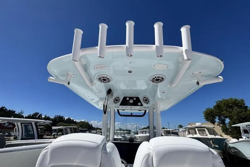 Slide: The Image of 2026 Sportsman Open 262 Center Console boat with rod holders and speakers under clear blue sky. - 31