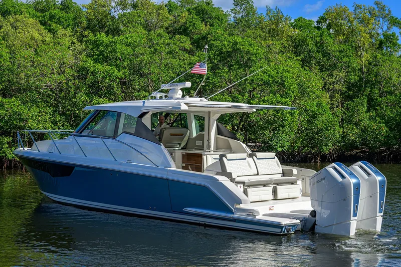 Slide: The Image of 2022 Tiara Yachts 43 LE cruising on a serene waterway with lush greenery. - 7