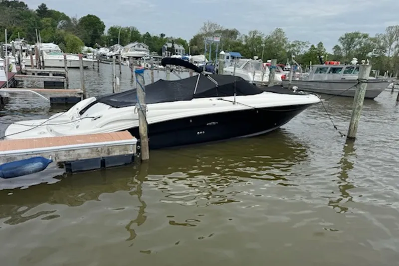 The Image of 2006 Sea Ray 290 SLX boat docked at a marina with covered seating area. - 0