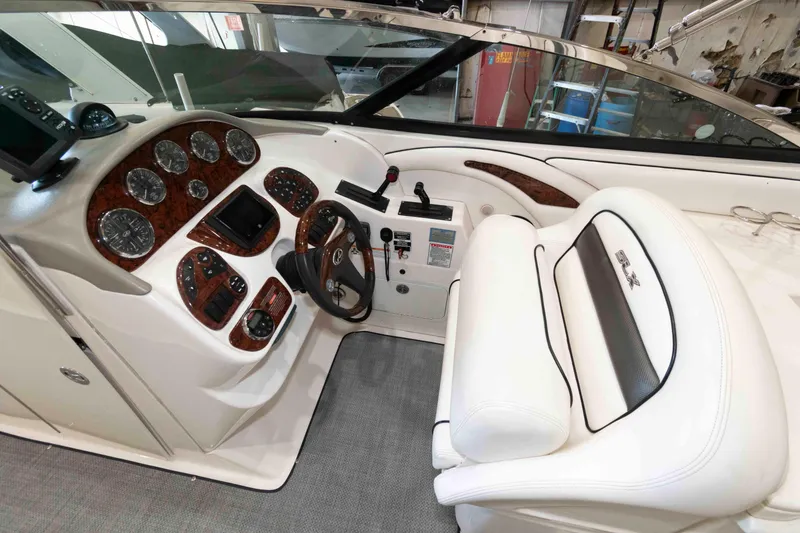 Slide: The Image of 2006 Sea Ray 290 SLX boat cockpit with white seating and wood-accented dashboard. - 8