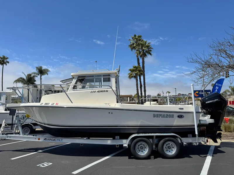 Slide: The Image of 2023 Defiance Admiral 220 EX boat docked at a marina, showcasing sleek design. - 2