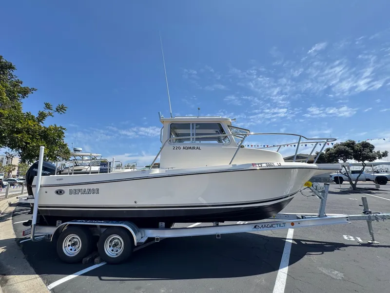 Slide: The Image of 2023 Defiance Admiral 220 EX boat docked at a marina under clear blue skies. - 7
