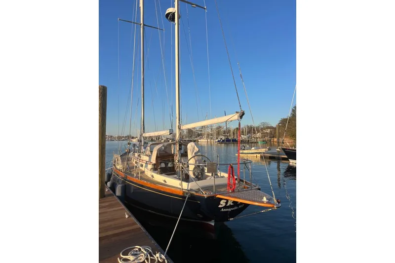 Slide: The Image of 1980 F&C 44 sailboat docked in a serene marina under clear blue skies. - 10