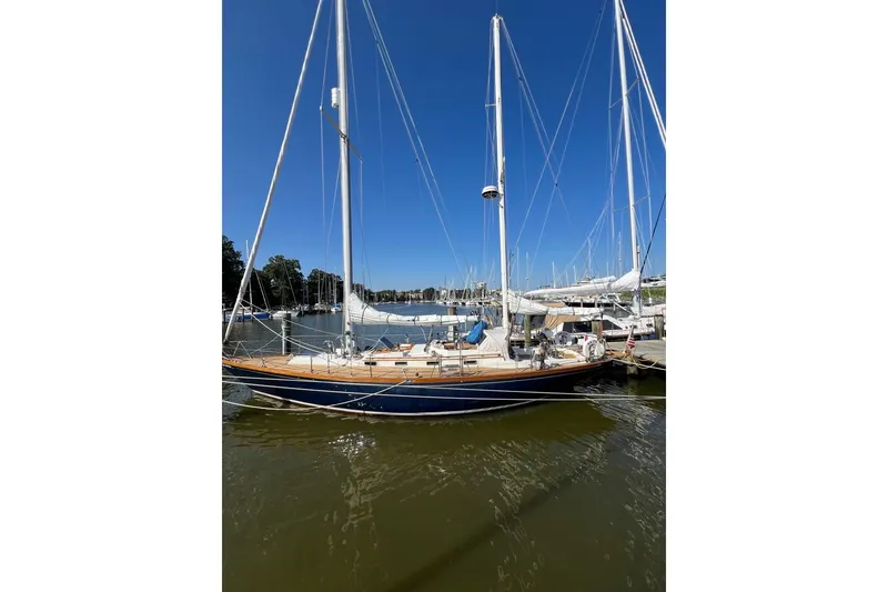 Slide: The Image of 1980 F&C 44 sailboat docked in a marina under clear blue skies. - 13