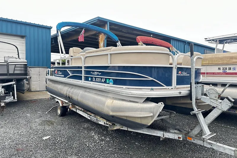 The Image of 2019 SUNTRACKER Party Barge Pontoon on trailer, parked near blue building. - 0
