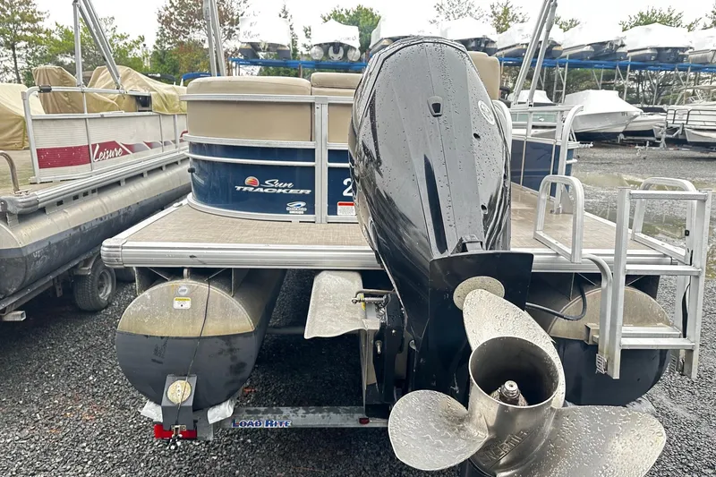 Slide: The Image of 2019 SUNTRACKER Party Barge Pontoon with outboard motor, parked on gravel lot. - 2