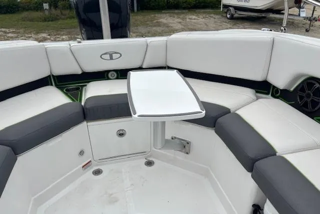 Slide: The Image of 2022 Tahoe 210 S boat interior with white and gray seating, small table, and cup holders. - 23